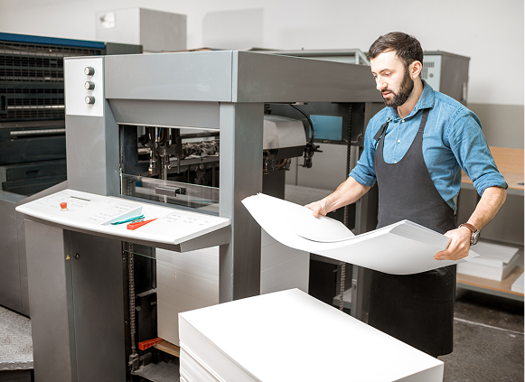 Worker handling paper in print shop